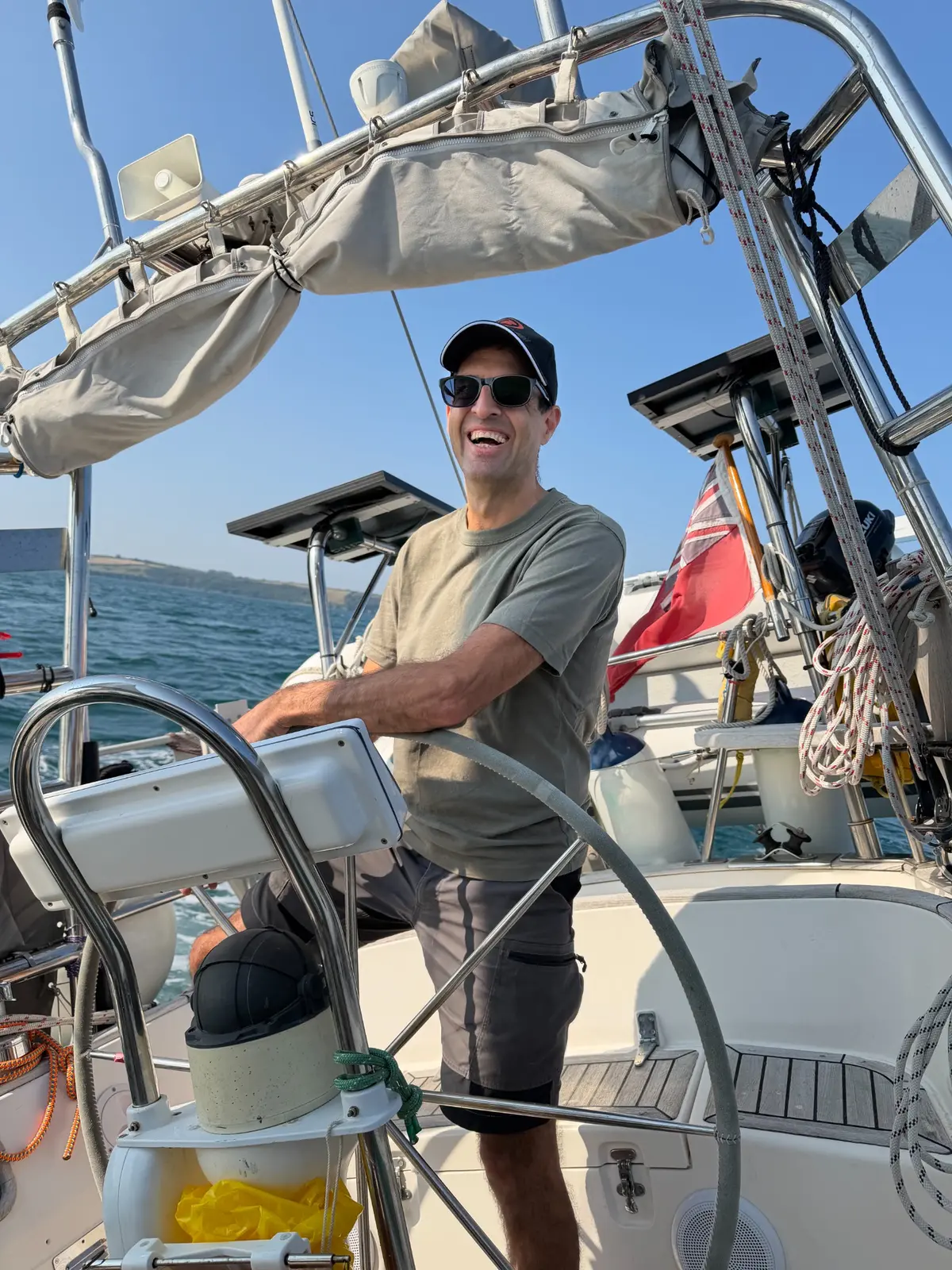 A sailor smiling while taking the helm aboard Suerte